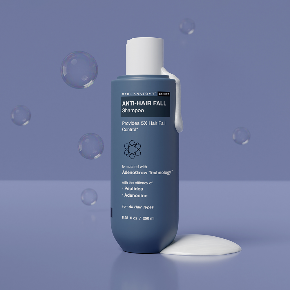 A bottle of anti-hairfall shampoo on a blue surface, designed to strengthen hair and reduce breakage effectively.

